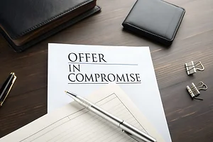 Offer in Compromise document on a wooden desk with office supplies.