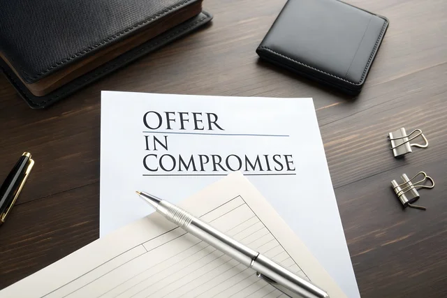 Offer in Compromise document on a wooden desk with office supplies.